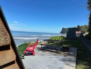 A patio with a picnic table and chairs overlooking a beach.