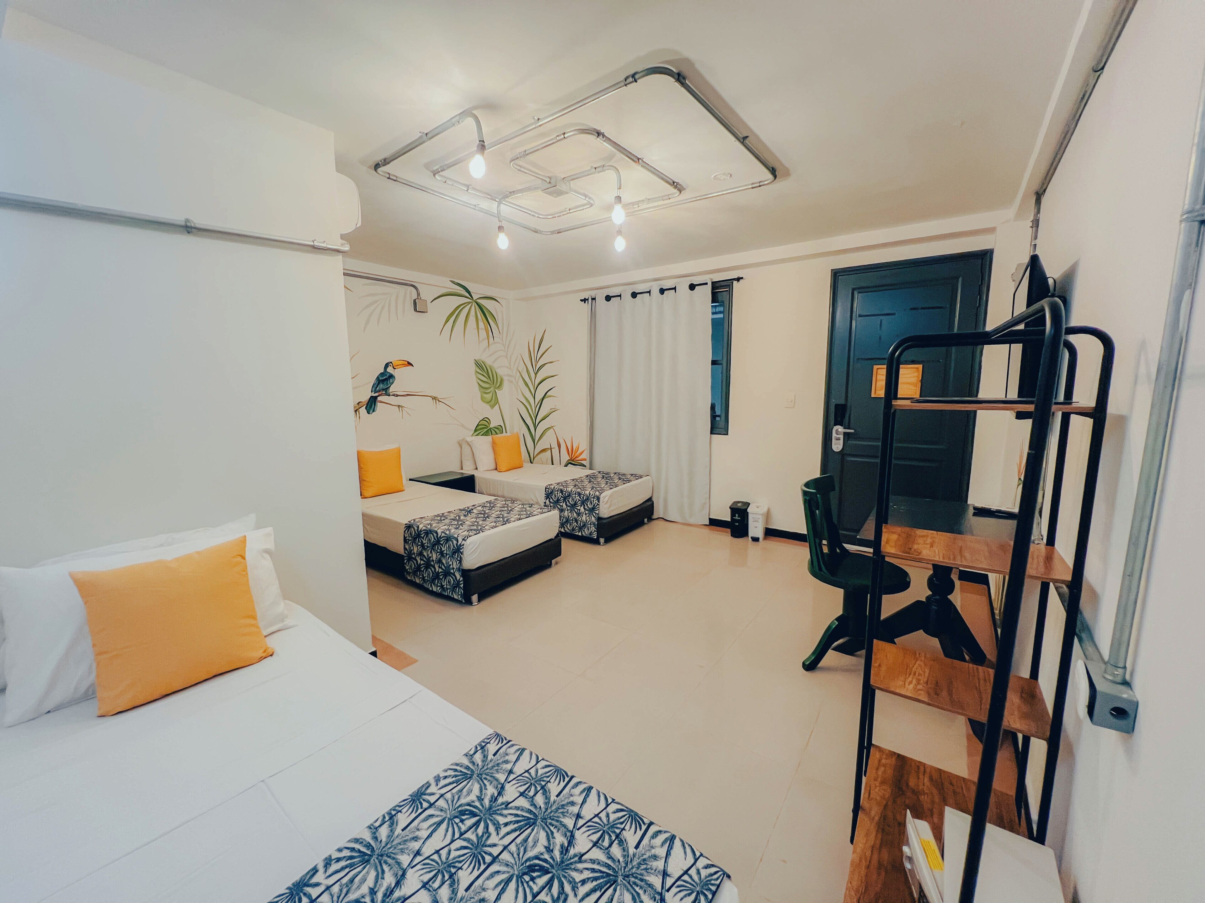A modern hotel room with two beds, a desk, and a bunk bed.