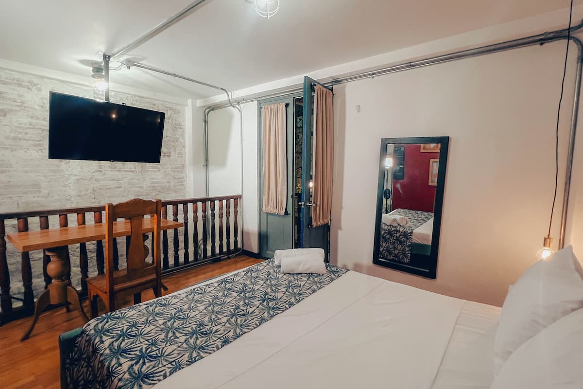 Une chambre d’hôtel avec un lit, un bureau, une chaise, une télévision et un balcon.