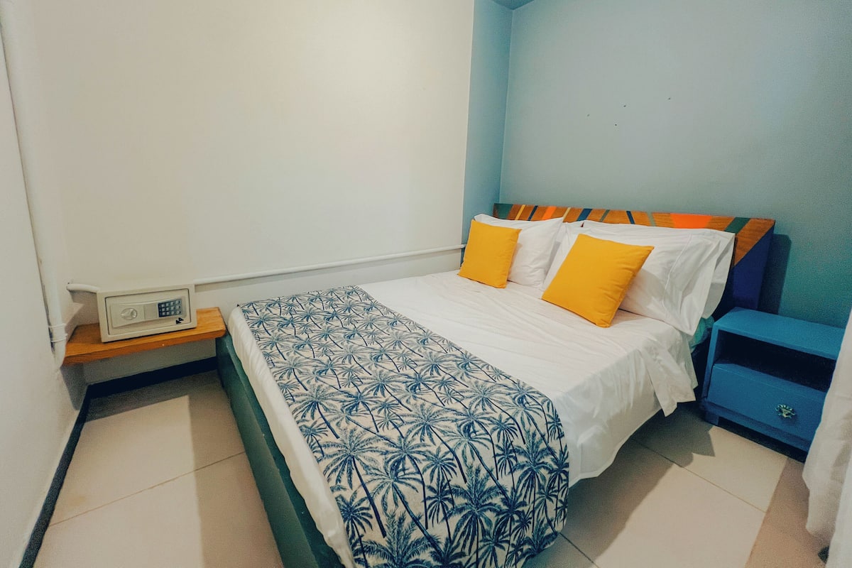 Une chambre à coucher comprenant un lit, une table de chevet, une commode et un réveil fixé au mur.