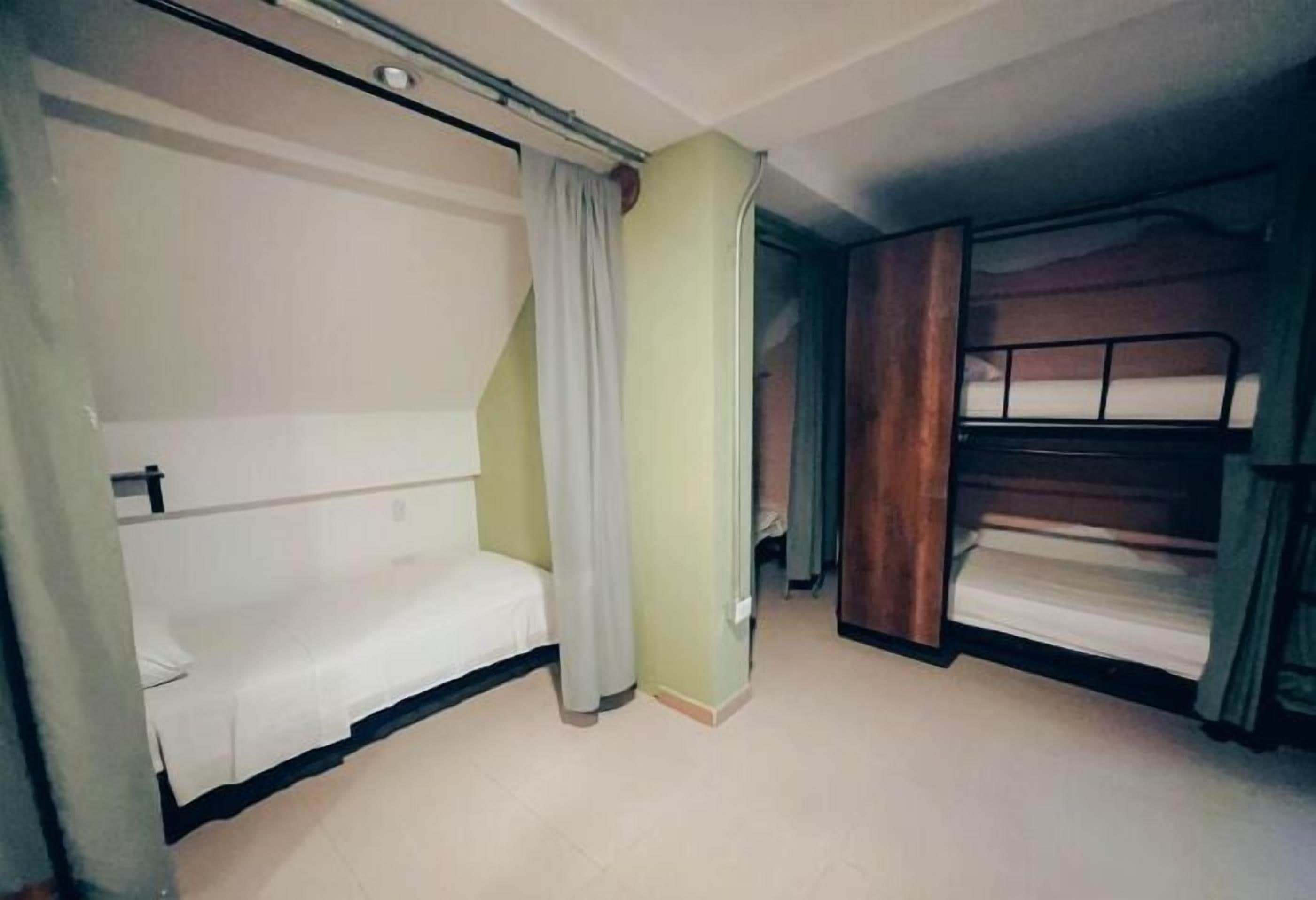 A room with bunk beds, a small seating area, and a curtain.