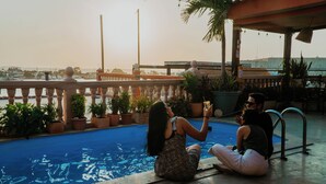 Zona de piscina con vista al mar, plantas en macetas y barandilla.