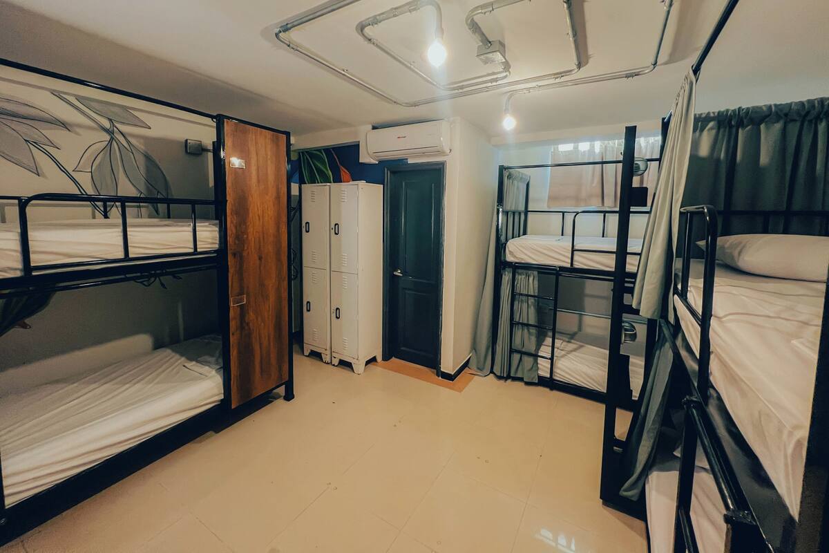 Une chambre de dortoir avec des lits superposés, une armoire en bois, une porte et un luminaire au plafond.