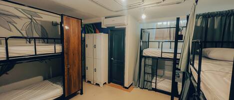 Un dormitorio con literas, un armario de madera, una puerta y una lámpara en el techo.