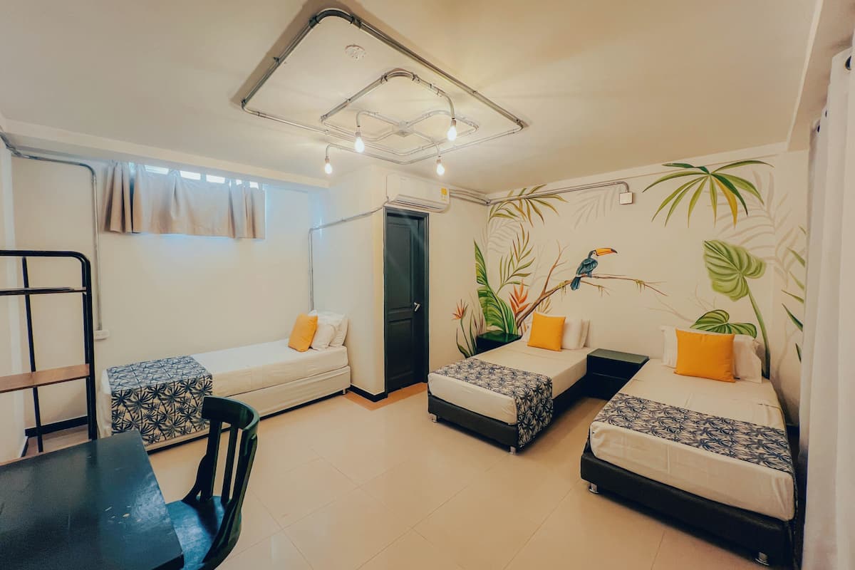 Une chambre de taille modeste, équipée de deux lits simples, d’une petite table et d’une chaise.