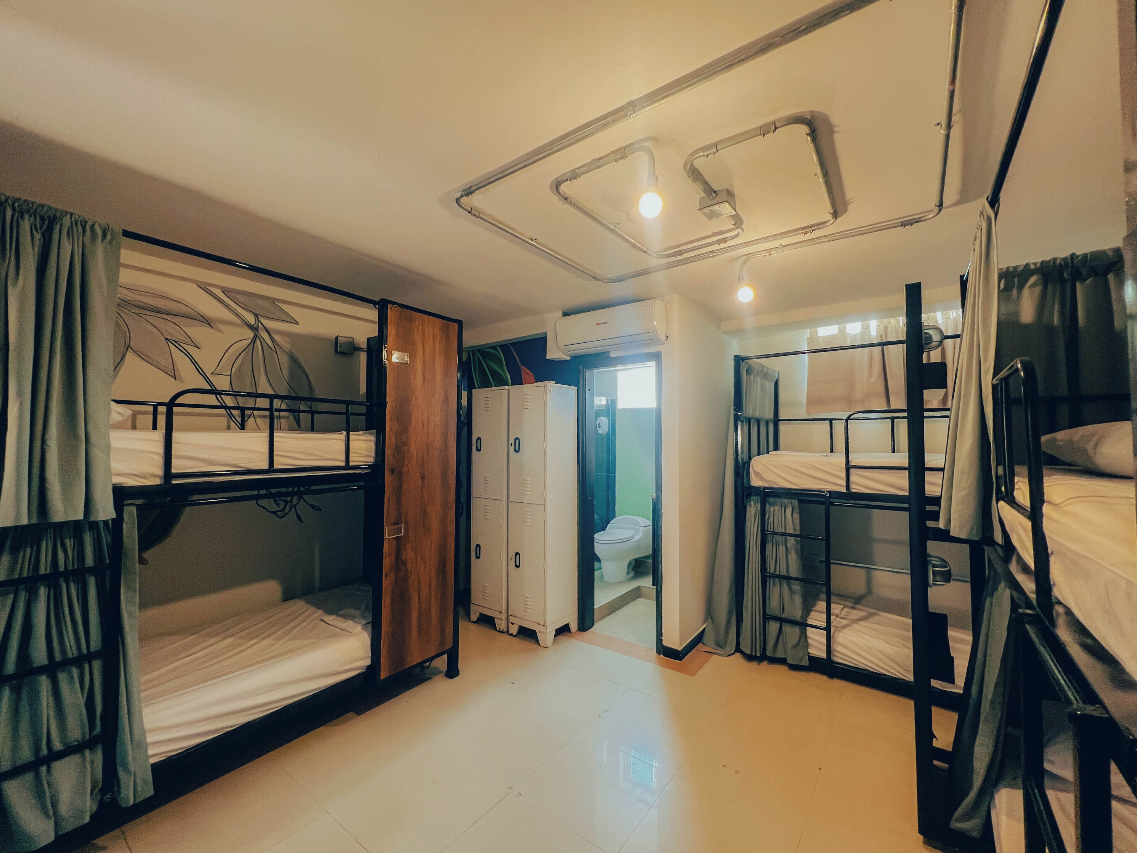 A dormitory room with bunk beds, a wardrobe, and a bathroom.