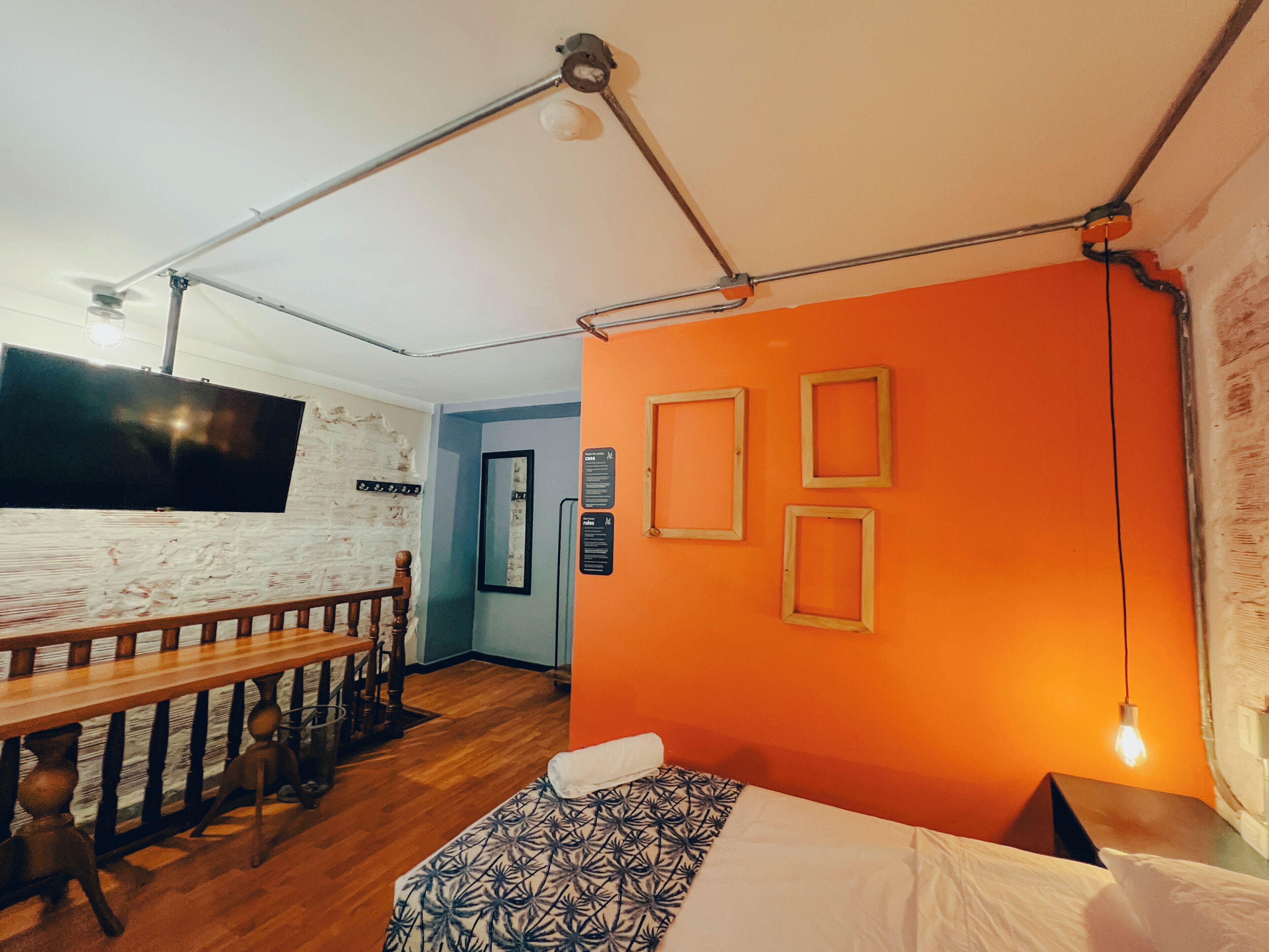 A room with a bed, a desk, a chair, and a TV mounted on the wall.
