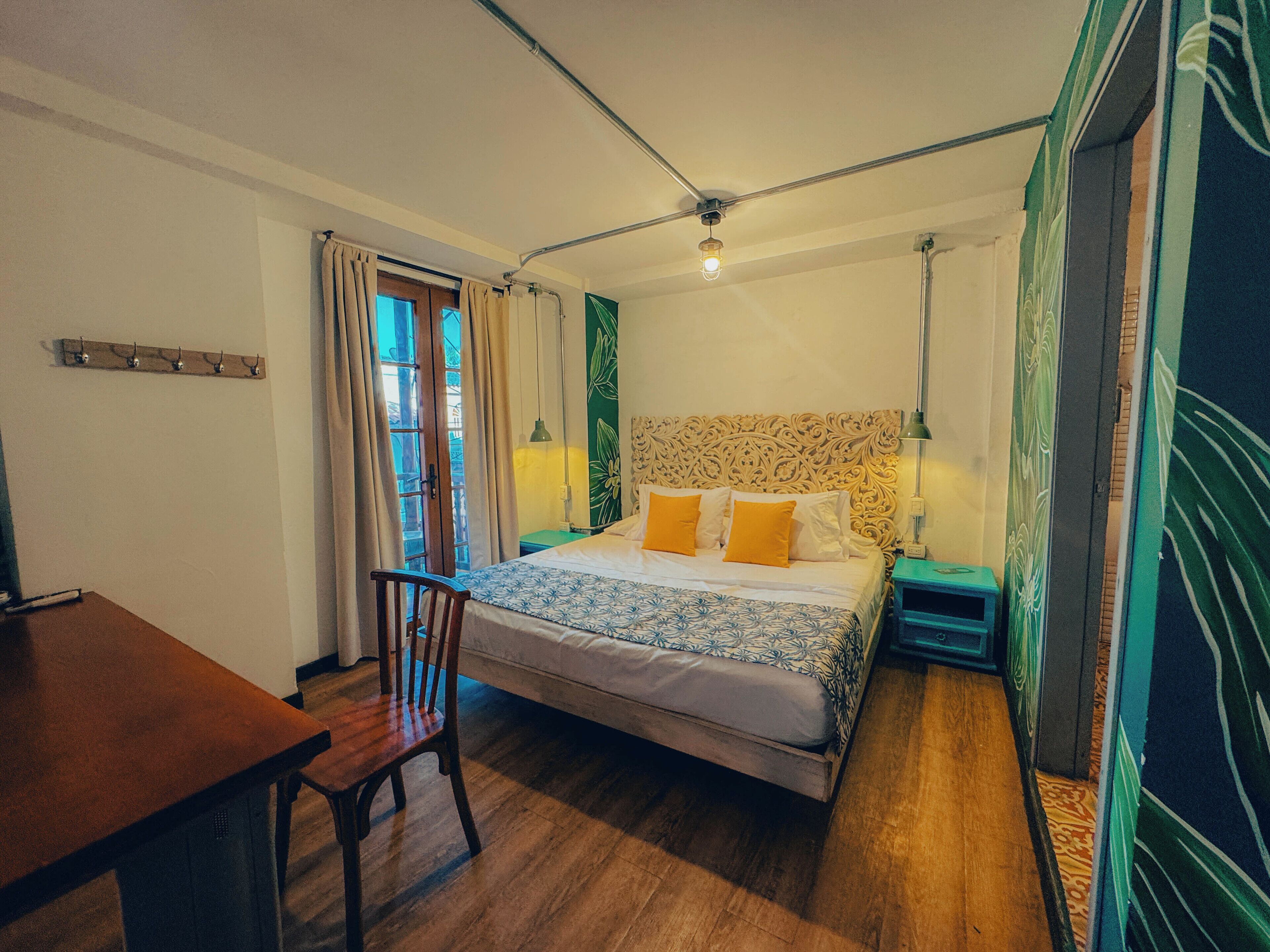 Ein Schlafzimmer mit Bett, Schreibtisch, Stuhl, Lampe und Deckenleuchte.