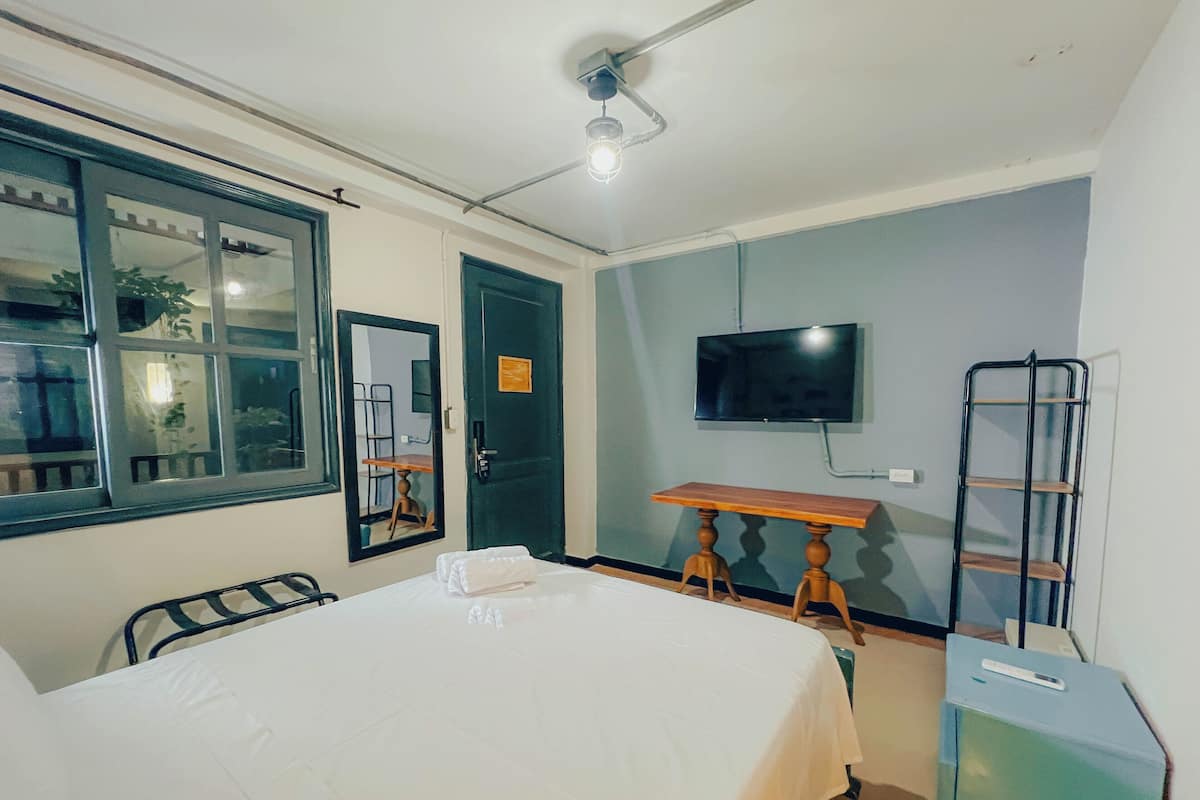 Une chambre à coucher avec un lit, une télévision, un bureau et une chaise.