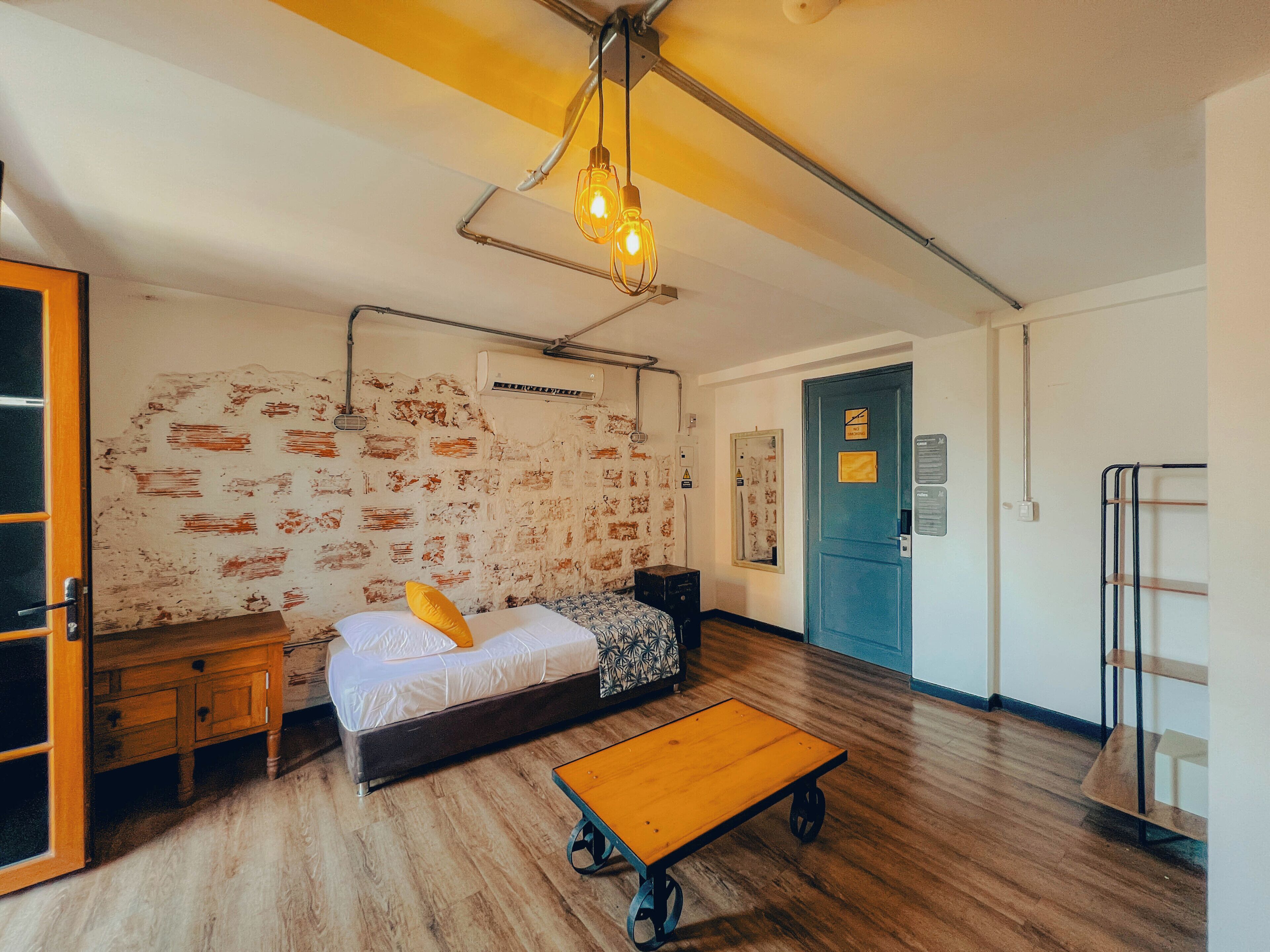 Um quarto com uma cama, uma mesa de madeira, um guarda-roupa e uma porta.