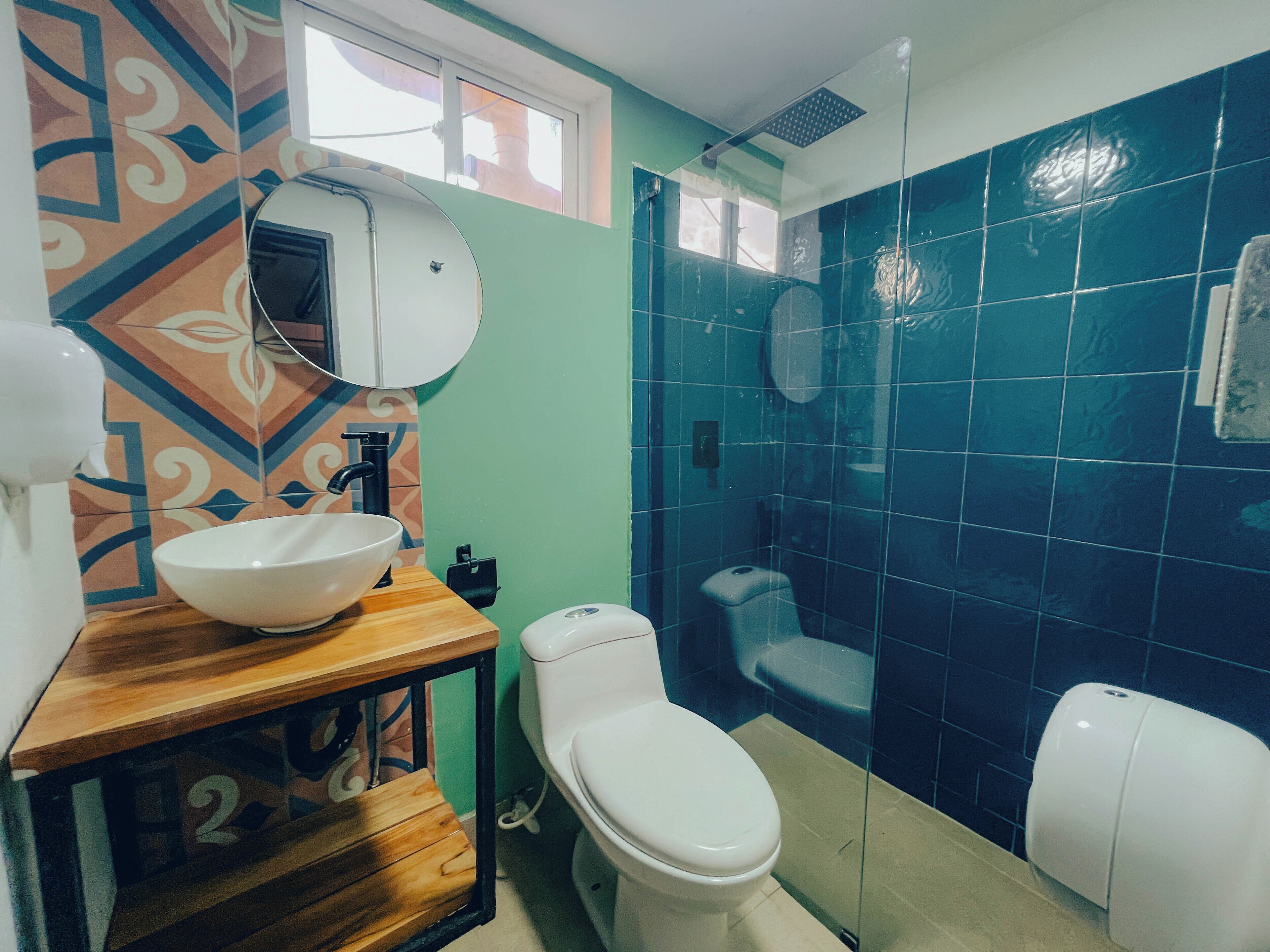 A bathroom with a wooden vanity, a white sink, and a toilet.
