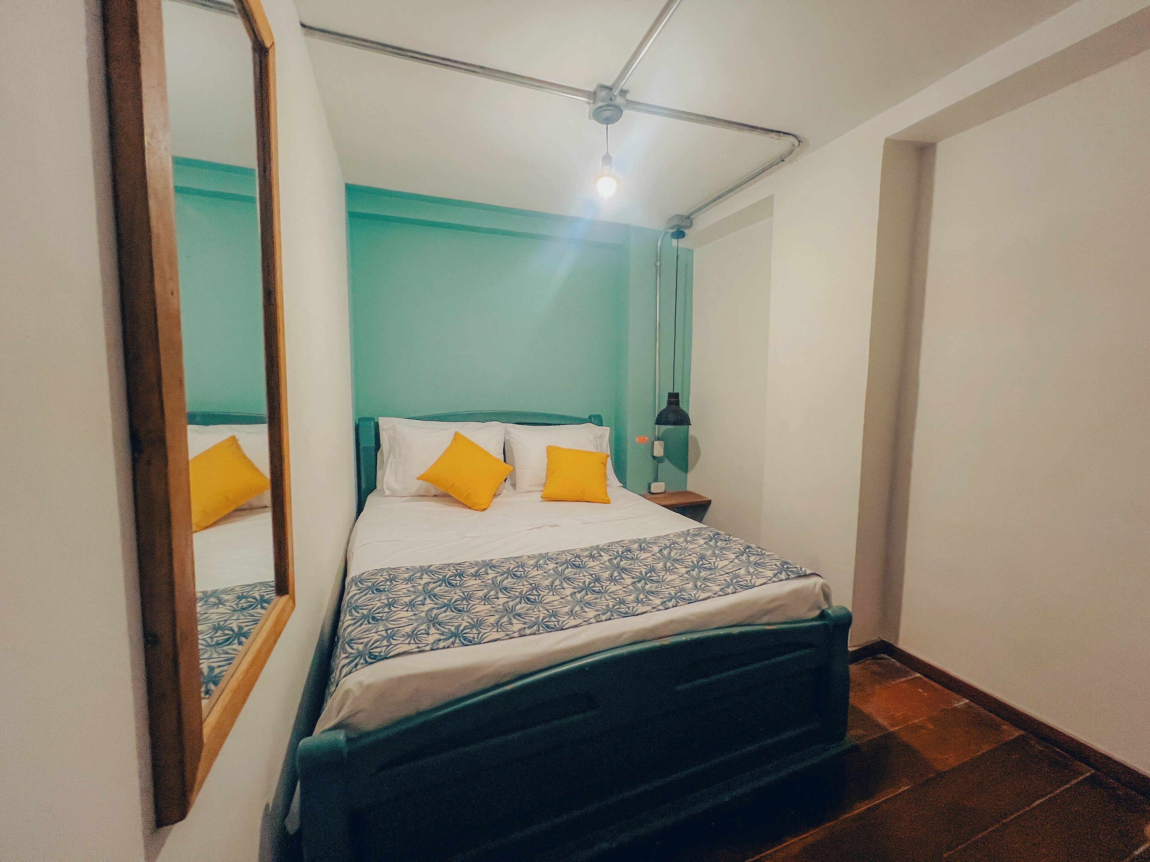 Un dormitorio con cama, mesita de noche, espejo y ventilador de techo.