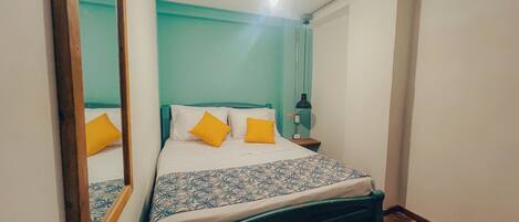 Un dormitorio con cama, mesita de noche, espejo y ventilador de techo.