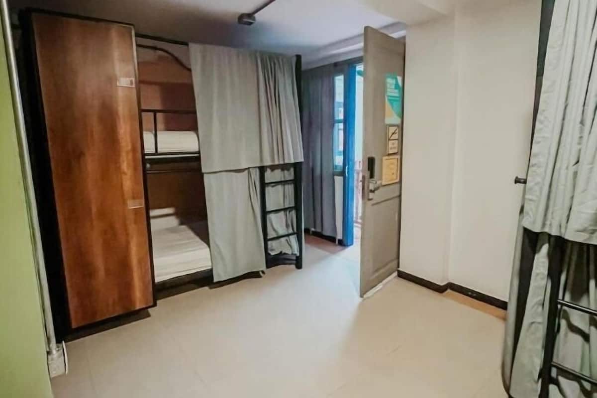 Une chambre avec des lits superposés, un ventilateur de plafond et une porte donnant sur une autre pièce.