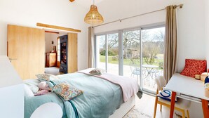 Un dormitorio con cama, escritorio, silla, estantería y un ventanal con vistas al exterior.