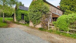 A stone building with a gravel path leading to it, surrounded by greenery.