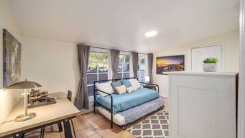 Ein Schlafzimmer mit einem Bett, einem Schreibtisch, einer Lampe und einem Fenster mit Vorhängen.