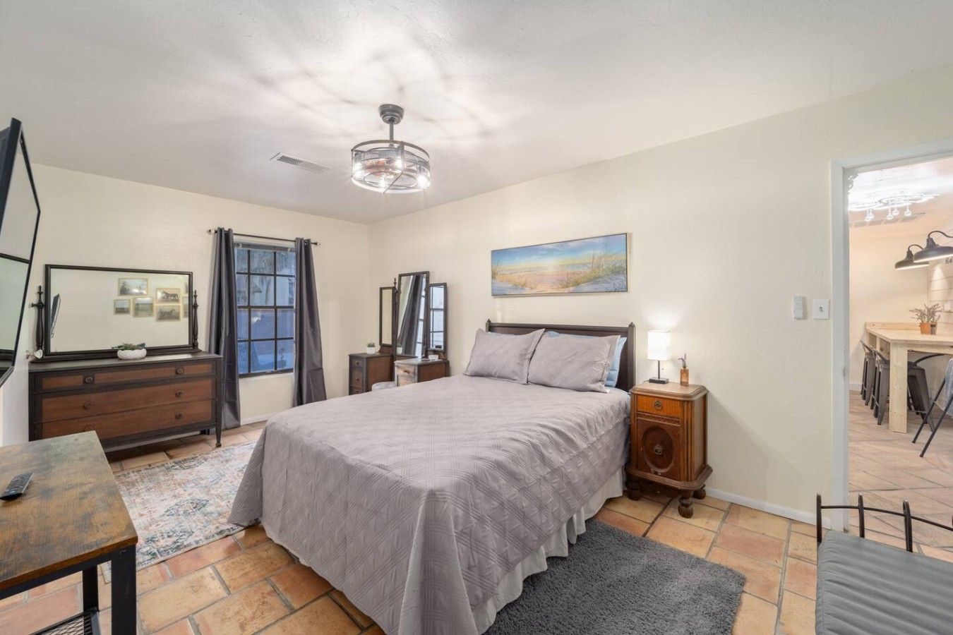 A bedroom with a bed, dresser, bedside tables, a desk, and a chair.