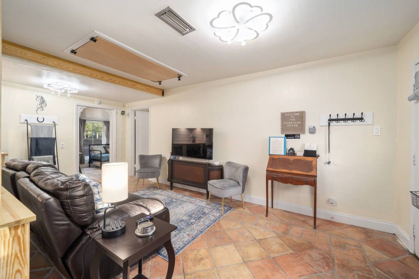 A living room with a leather sofa, a TV, a small table, and a rug.