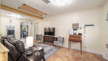 A living room with a leather sofa, a TV, a small table, and a rug.