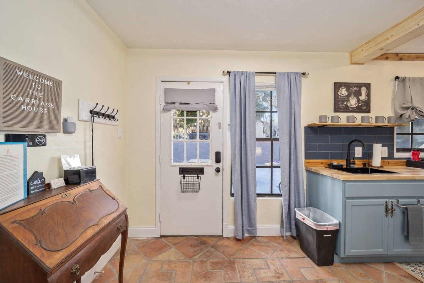 A kitchen with a wooden counter, a sink, and a window with curtains.