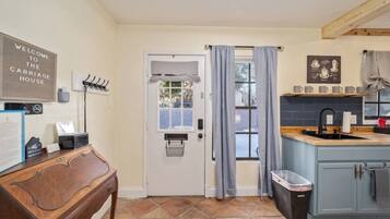 A kitchen with a wooden counter, a sink, and a window with curtains.
