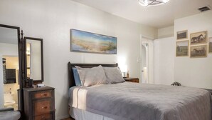 Un dormitorio con cama, cómoda, espejo y obras de arte en la pared.