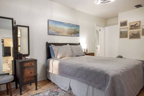 Un dormitorio con cama, cómoda, espejo y obras de arte en la pared.