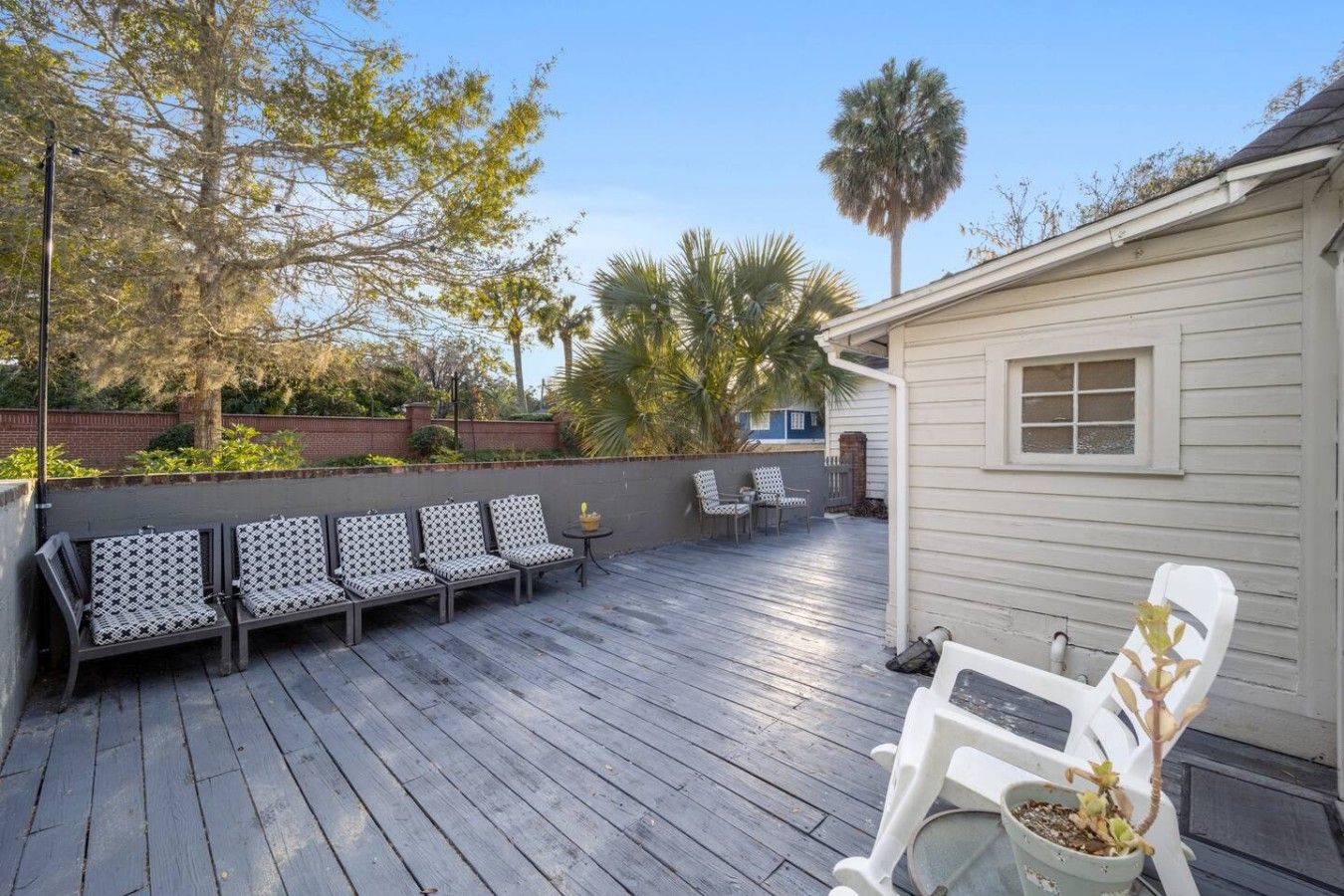 A wooden deck with outdoor seating, a small building, and surrounding vegetation.
