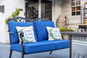 A blue outdoor sofa with two cushions, one with a floral design and the other with a motivational quote. - Kemp Estate Carriage House | Downtown Ocala 2/1 (Ocala)