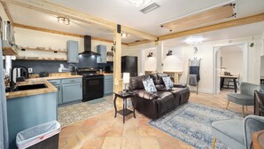 A spacious living area with a leather sofa, a dining table, and a kitchen in the background.