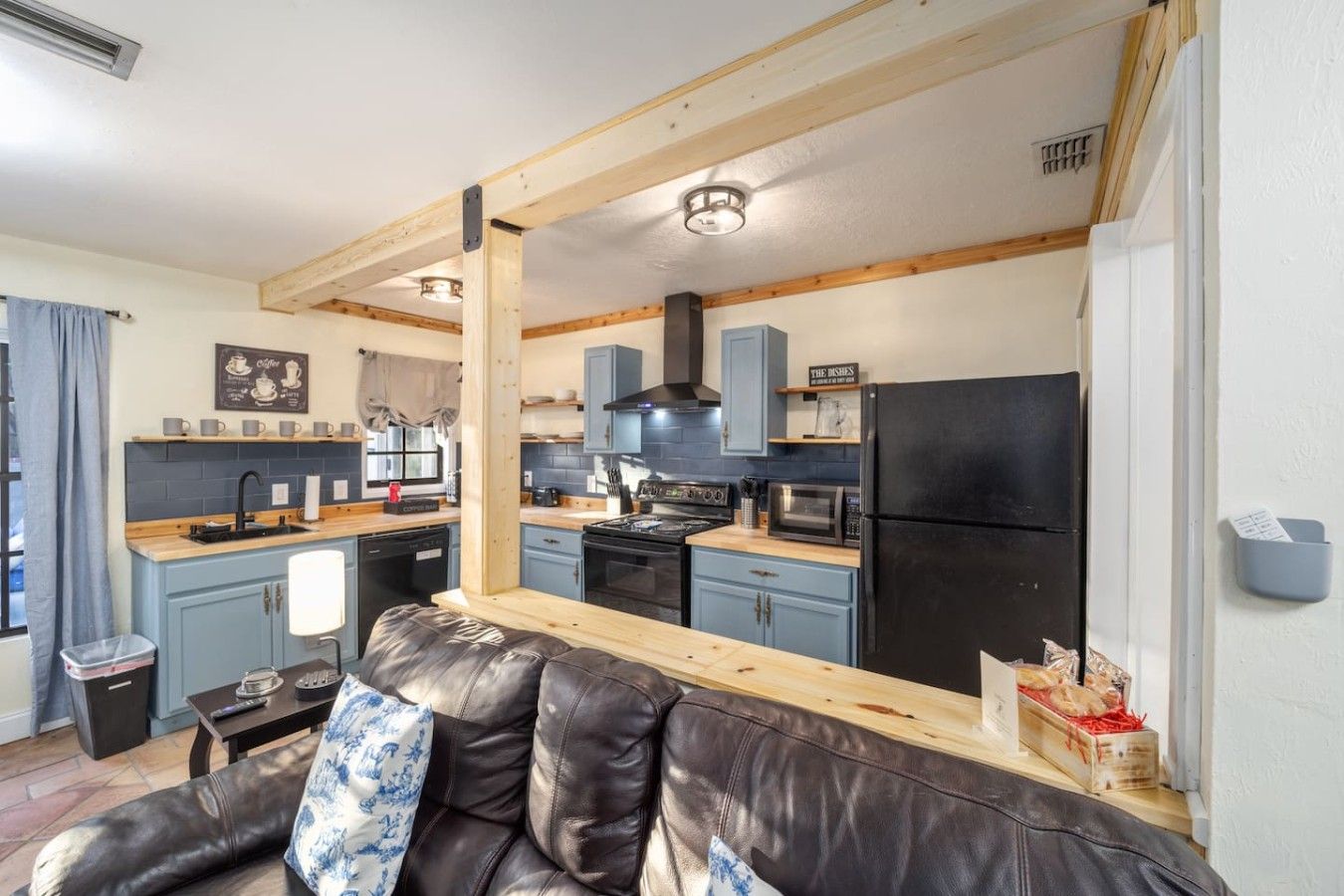 A compact kitchen with a black refrigerator, wooden cabinets, and a black stove.