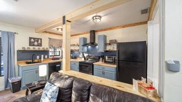A compact kitchen with a black refrigerator, wooden cabinets, and a black stove.