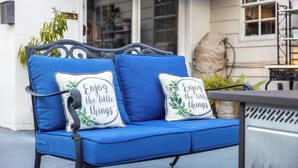 A blue outdoor sofa with cushions that say "Enjoy the little things."