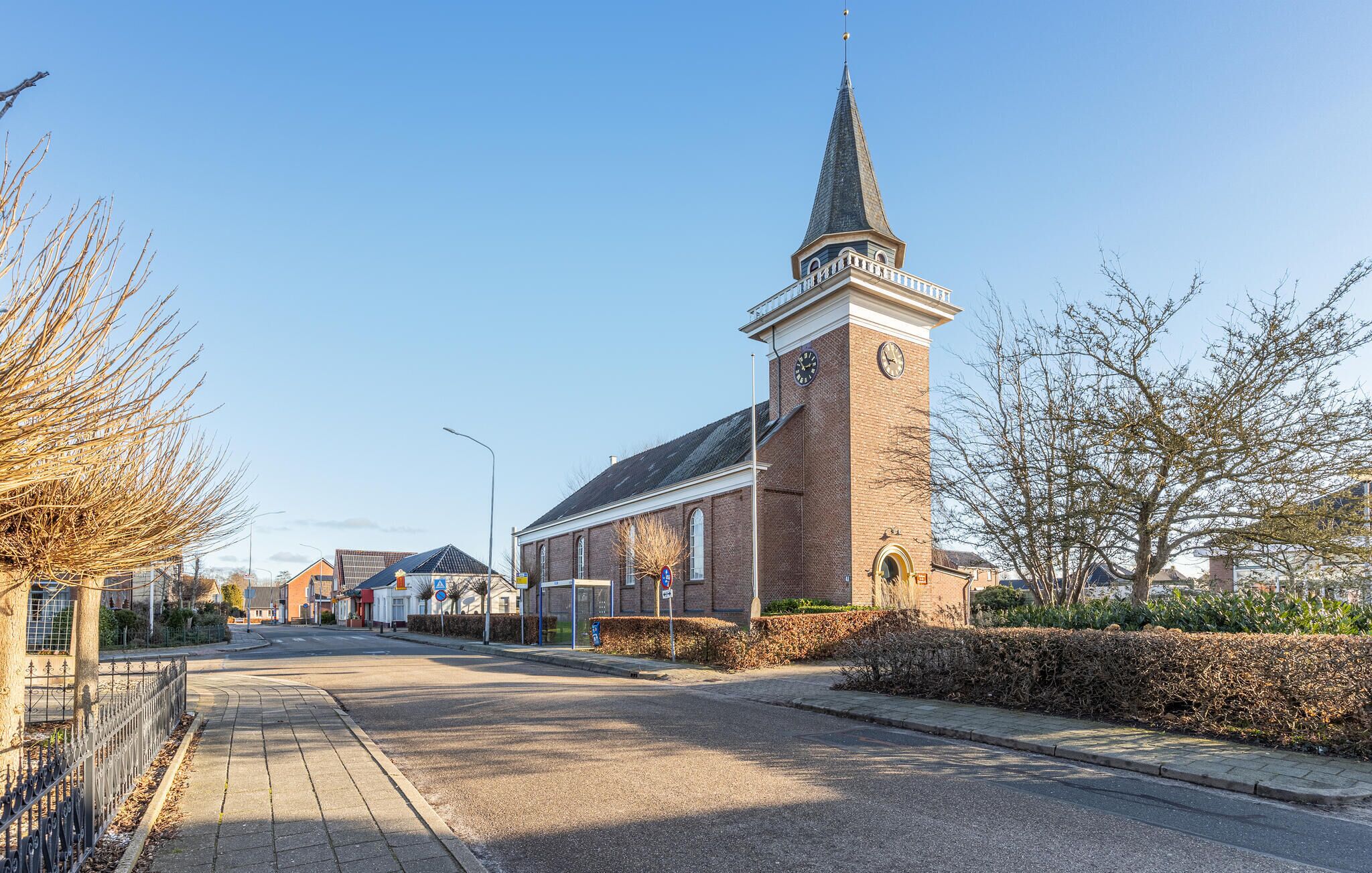 Straatbeeld met een kerk, herkenbaar aan de hoge spits en de klok.