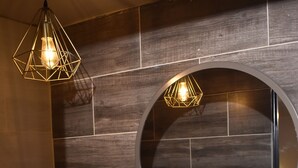 A bathroom with a round mirror, a sink, and two pendant lights. - History Center Hotel (Medellín)