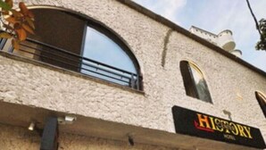 A building with a textured facade, arched windows, and a storefront with a sign reading "HISTORY." - History Center Hotel (Medellín)