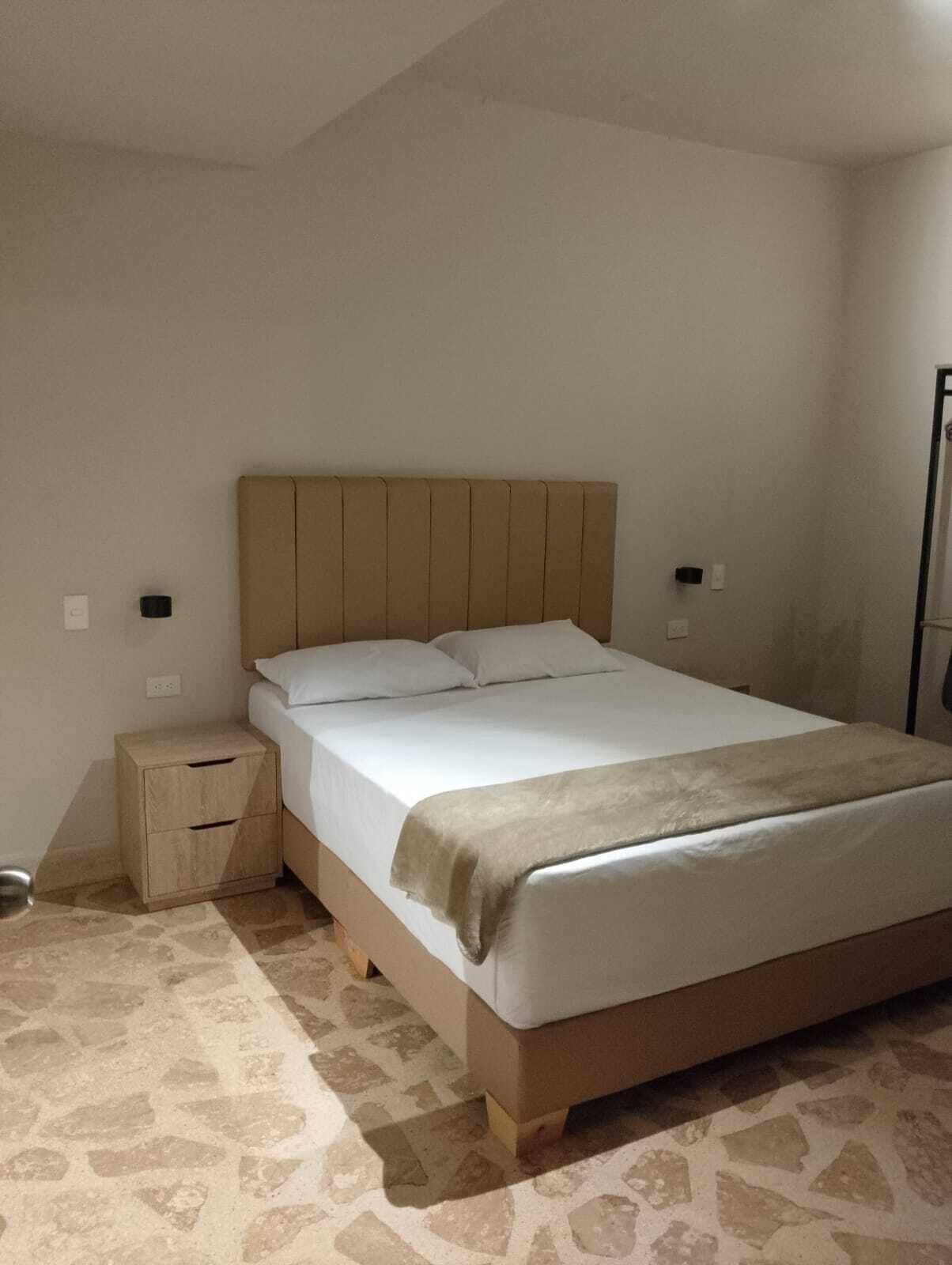 A bedroom with a bed, a nightstand, and a wall-mounted light.