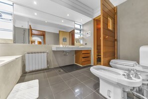 Une salle de bain moderne équipée d’une baignoire, de toilettes, d’un bidet et d’un meuble-lavabo.