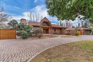 Une maison en briques avec un toit en pente, une porte d’entrée en bois et une allée pavée.