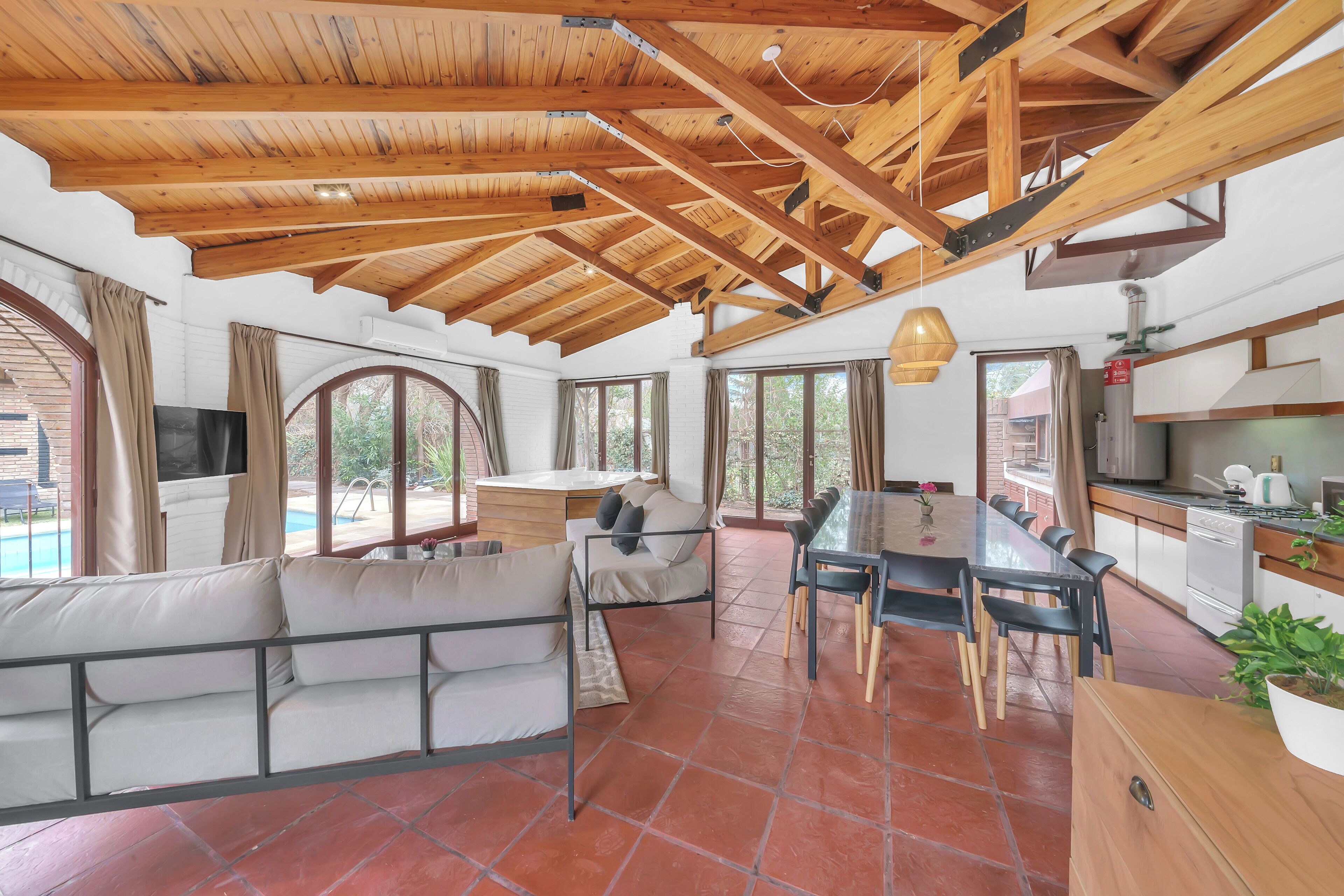A spacious living area with a wooden ceiling, a dining table, and a sofa.