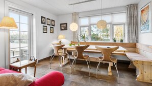 A modern dining area with a wooden bench, chairs, and a table. There are framed pictures on the wall and a window with curtains. - Nice home in Farsø with WiFi (Farsø)