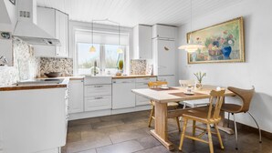 A modern kitchen with white cabinets, a dining table with chairs, and a painting on the wall. - Nice home in Farsø with WiFi (Farsø)