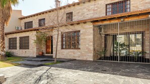 A two-story building with a brick facade, large windows with metal grilles, and a covered patio area. - MOT Erlich Wine House (Mendoza)