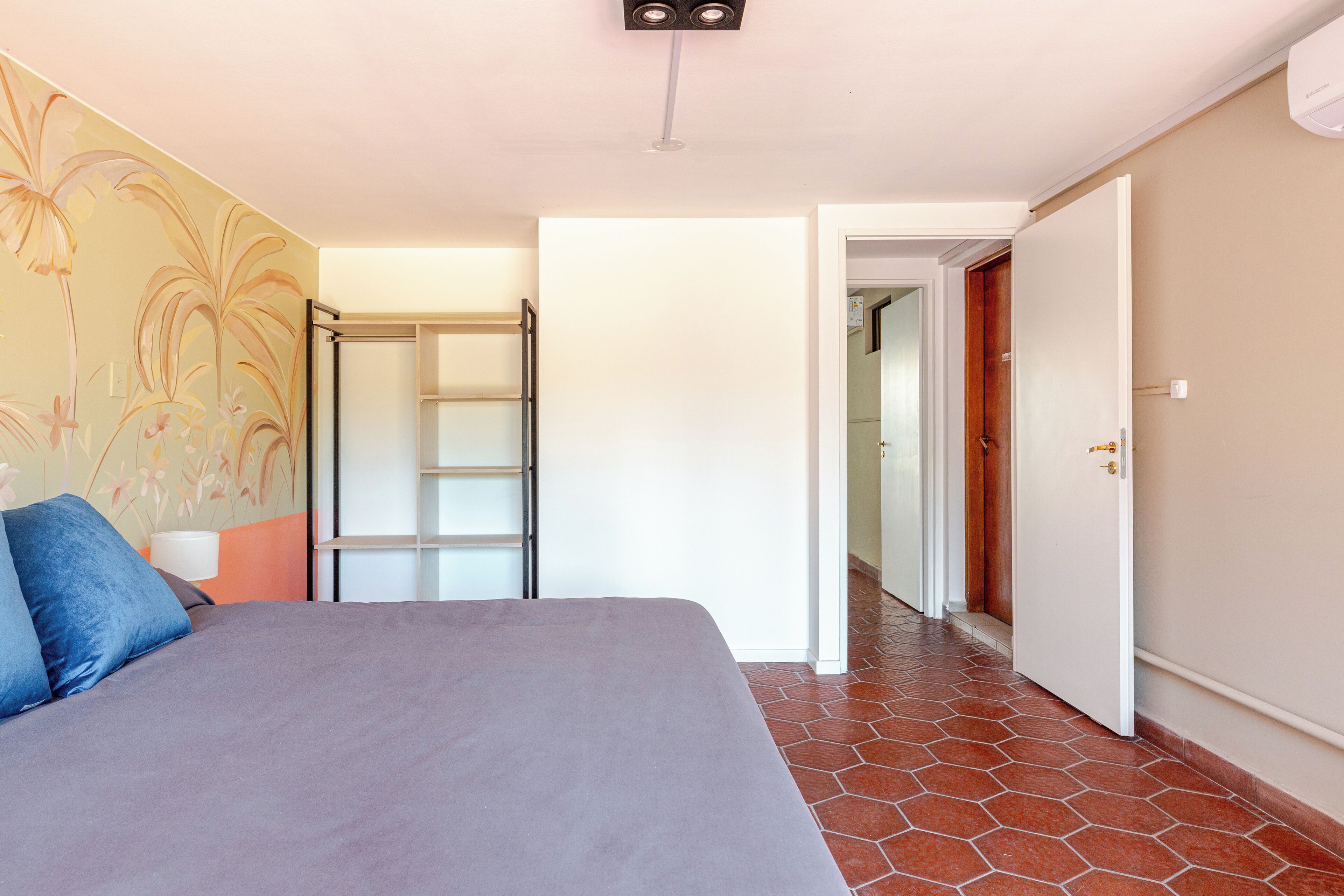 Un dormitorio con cama, armario y puerta al baño.
