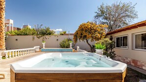 A wooden hot tub in a backyard with a pool, surrounded by plants and a tree. - MOT Erlich Wine House (Mendoza)