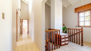 A spacious hallway with a wooden staircase, a large window with decorative glass, and a potted plant. - MOT Erlich Wine House (Mendoza)