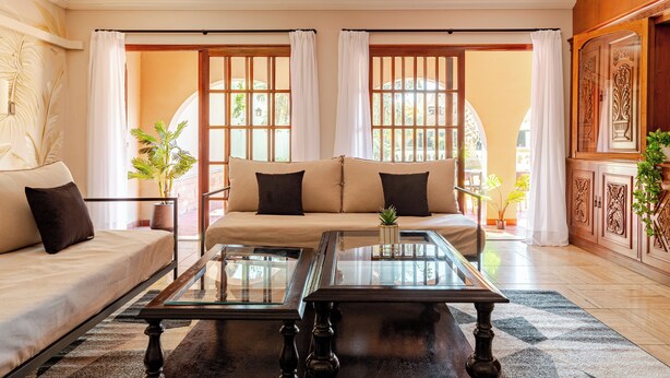 A living room with a sofa, two coffee tables, and a view of the outside through large windows. - MOT Erlich Wine House (Mendoza)