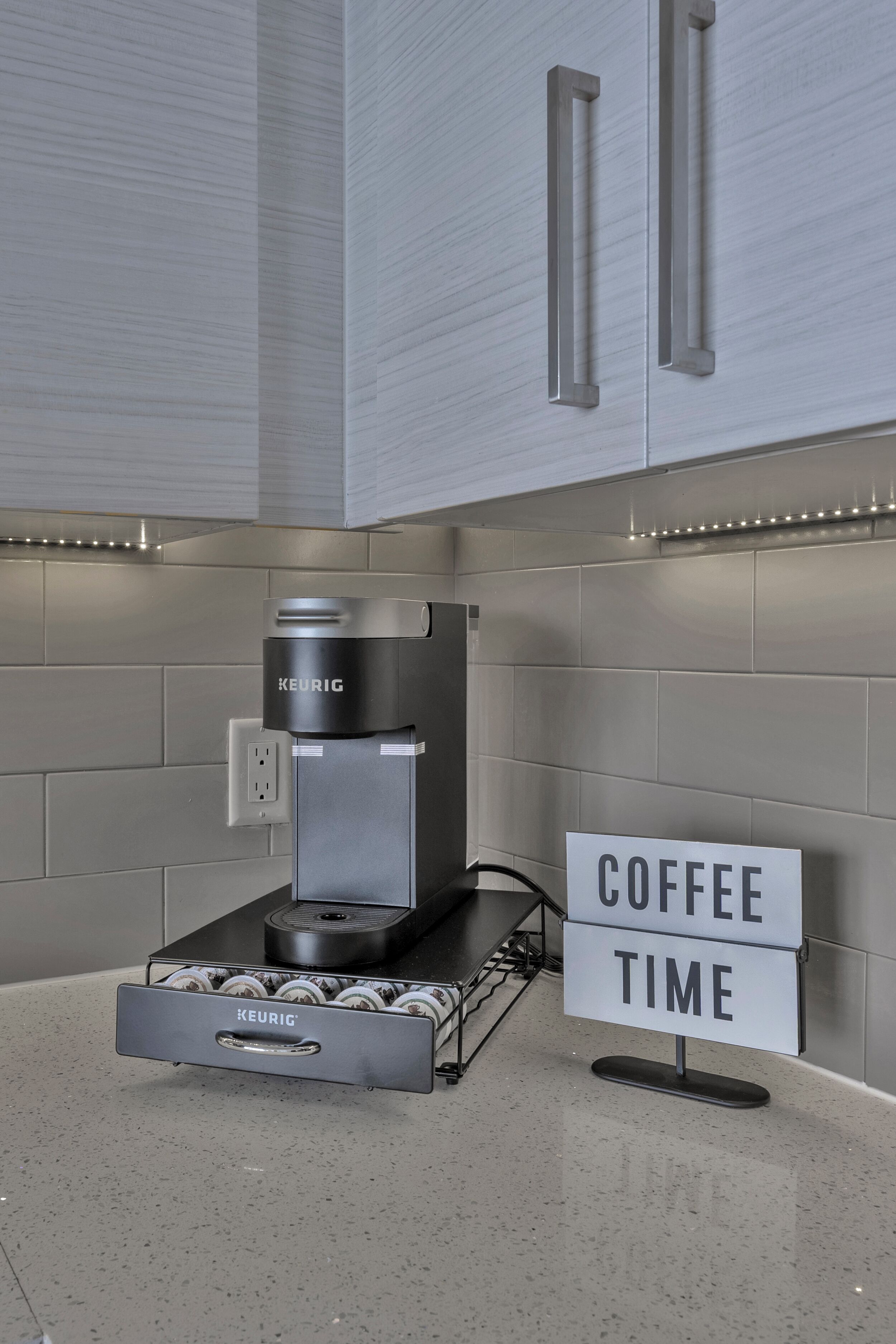 A modern kitchen with a Keurig coffee machine, a coffee pod holder, and a sign that reads "COFFEE TIME".