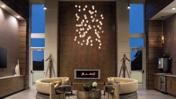 A modern living room with a large TV, two sofas, a coffee table, and a unique light fixture. - Downtown High-Rise w/ City Views, Pool & Gym (Atlanta)